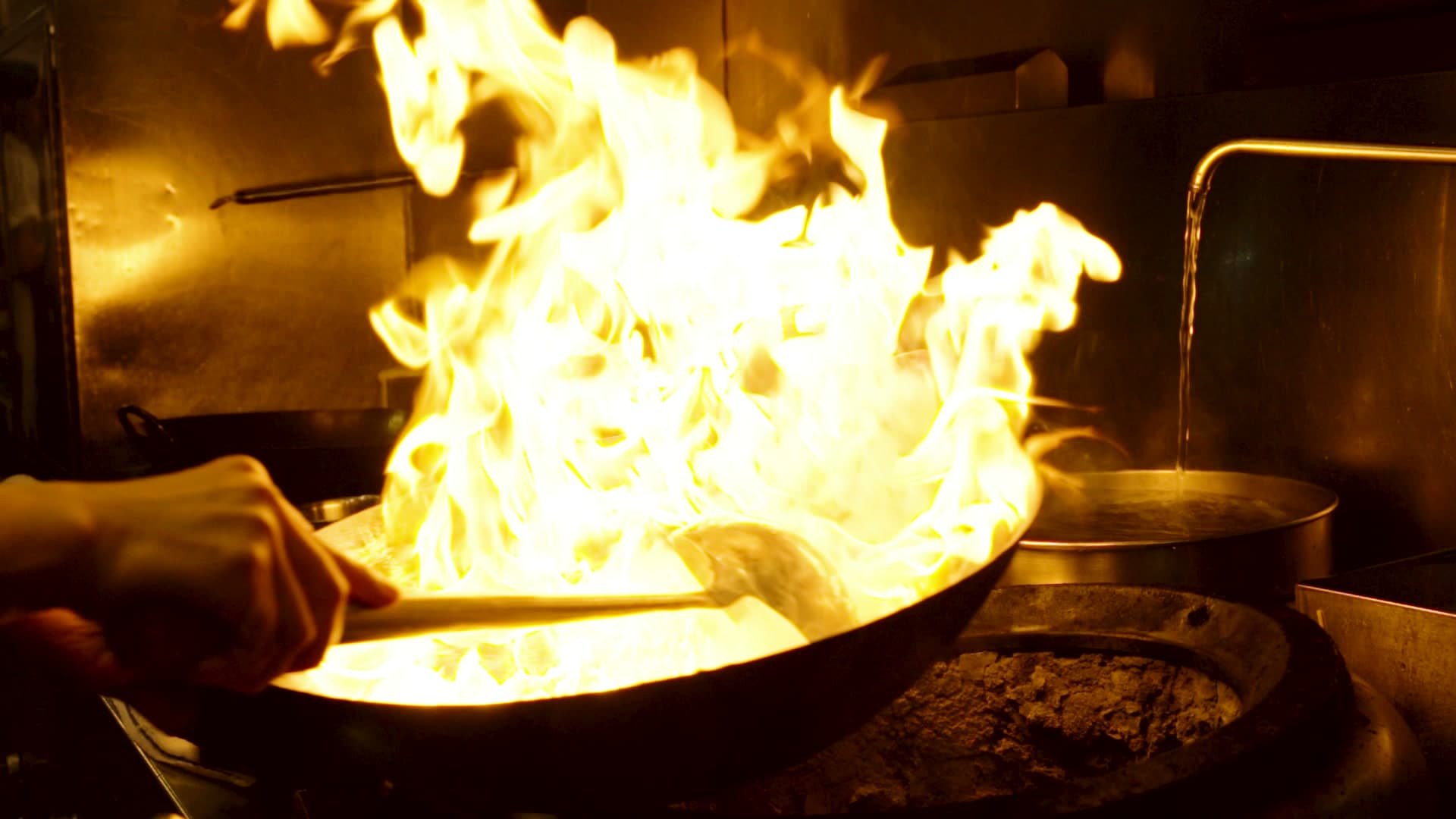 A wok flares up in a burst of open flame in a Hong Kong street-food kitchen, a frame from the studio's self-initiated Hong Kong film.